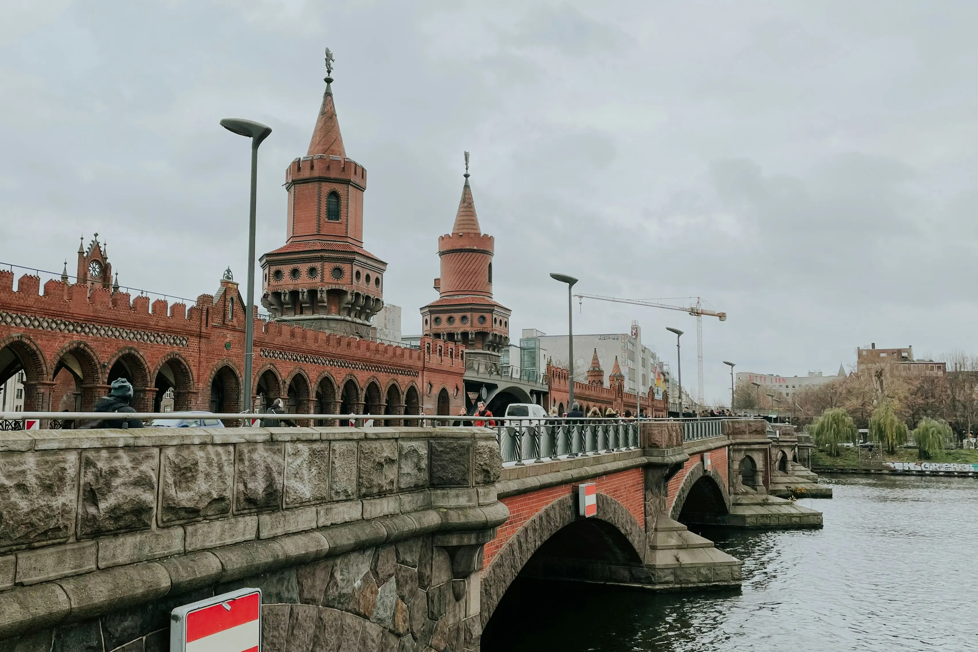 Most w Berlinie Most w Berlinie, pochmurna pogoda, w oddali widać zabudowania i dźwig przemysłowy.
